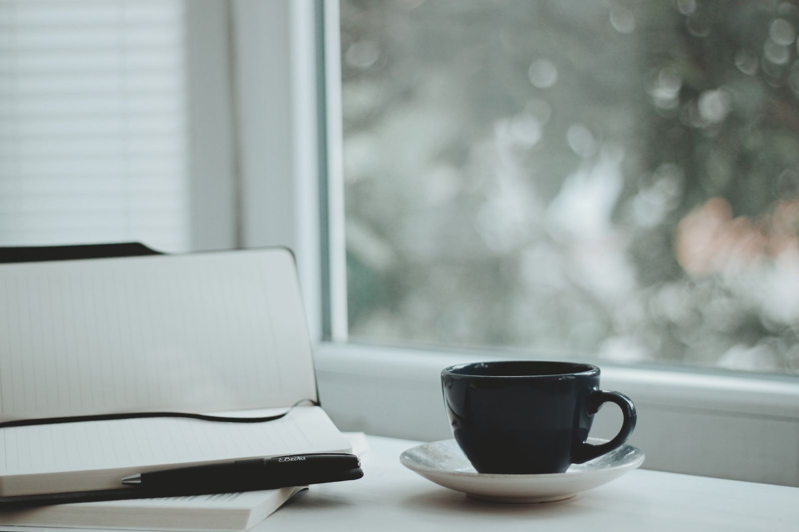 A dark cup and saucer on a windowsill in soft morning light.